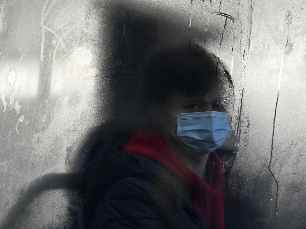 A commuter masks up for a bus ride in Liverpool, England. The omicron variant of the coronavirus has surged in the U.K. and is now dominant in the U.S. as well. There's now data indicating just how severe its symptoms might be.