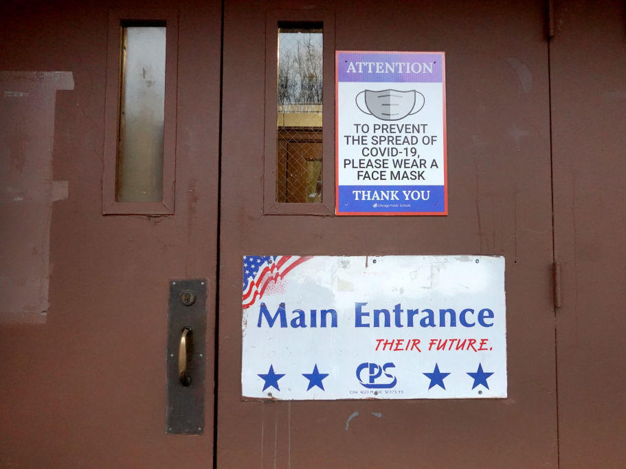 A sign on the door of Lowell Elementary School asks students, staff and visitors to wear a mask to prevent the spread of COVID-19 on Wednesday in Chicago. Classes at all of Chicago public schools have been canceled Wednesday by the school district after the teachers union voted to return to virtual learning.
