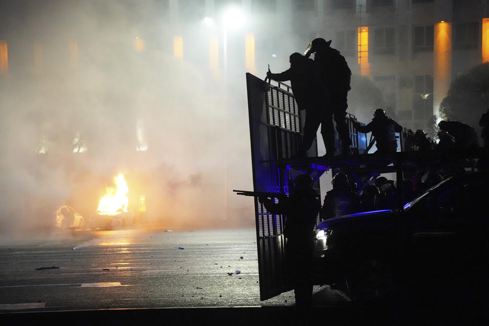 A police car on fire as riot police prepare to stop protesters in the center of Almaty, Kazakhstan, on Wednesday. Local news reports said police dispersed a demonstration of about 1,000 people and detained protesters Tuesday night in Almaty.