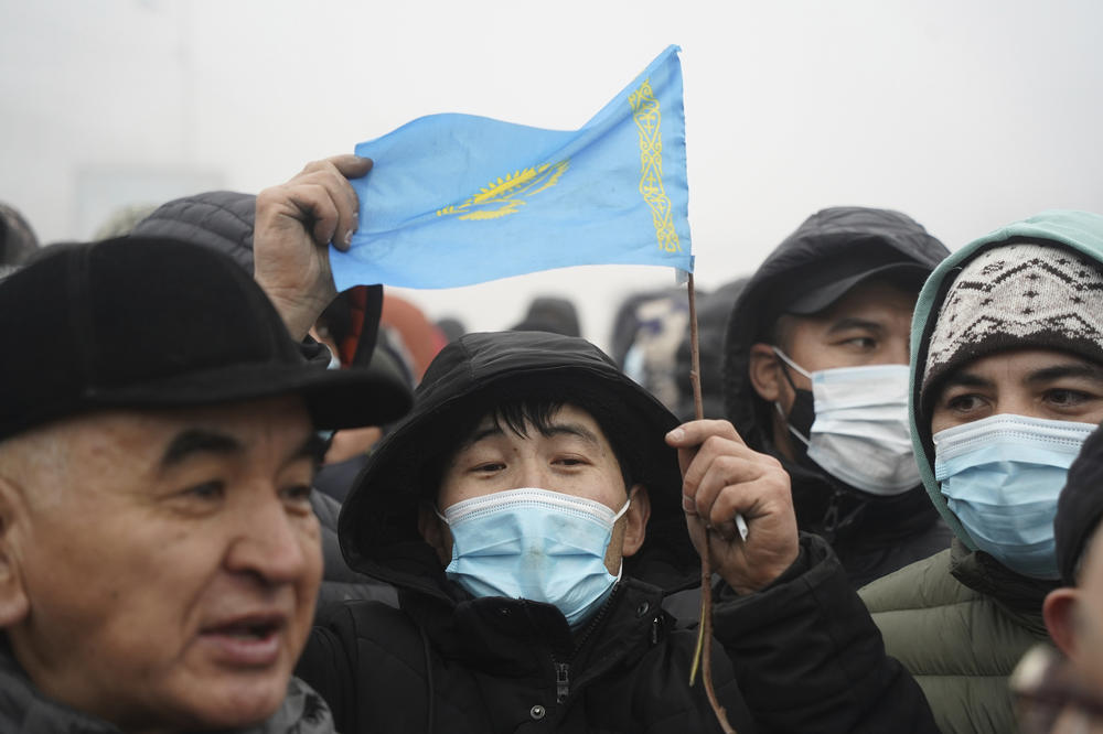 A person holding Kazakhstan's flag gathers with other protesters near a police line in Almaty, Kazakhstan, Wednesday. Demonstrators denouncing the surge in prices for liquefied petroleum gas have clashed with police in Kazakhstan's largest city and held protests in about a dozen other cities in the country.