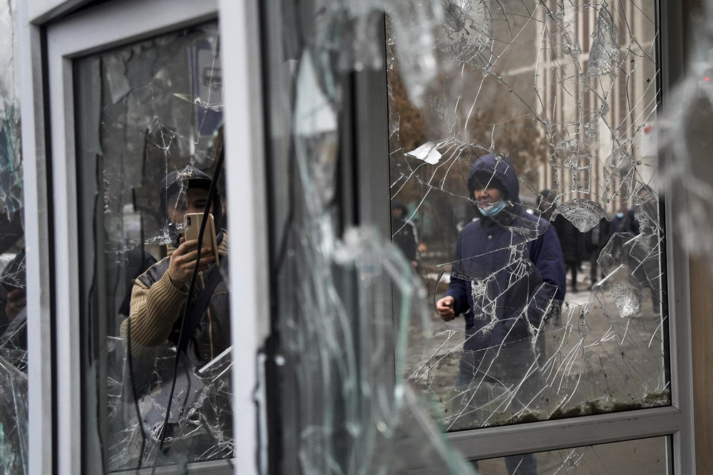 A man takes a photo of windows of a police kiosk damaged by demonstrators during a protest in Almaty, Kazakhstan, on Wednesday.