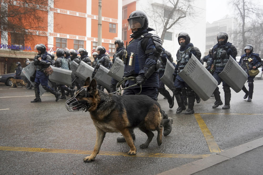 Riot police march to disperse demonstrators gathering in Almaty, Wednesday.