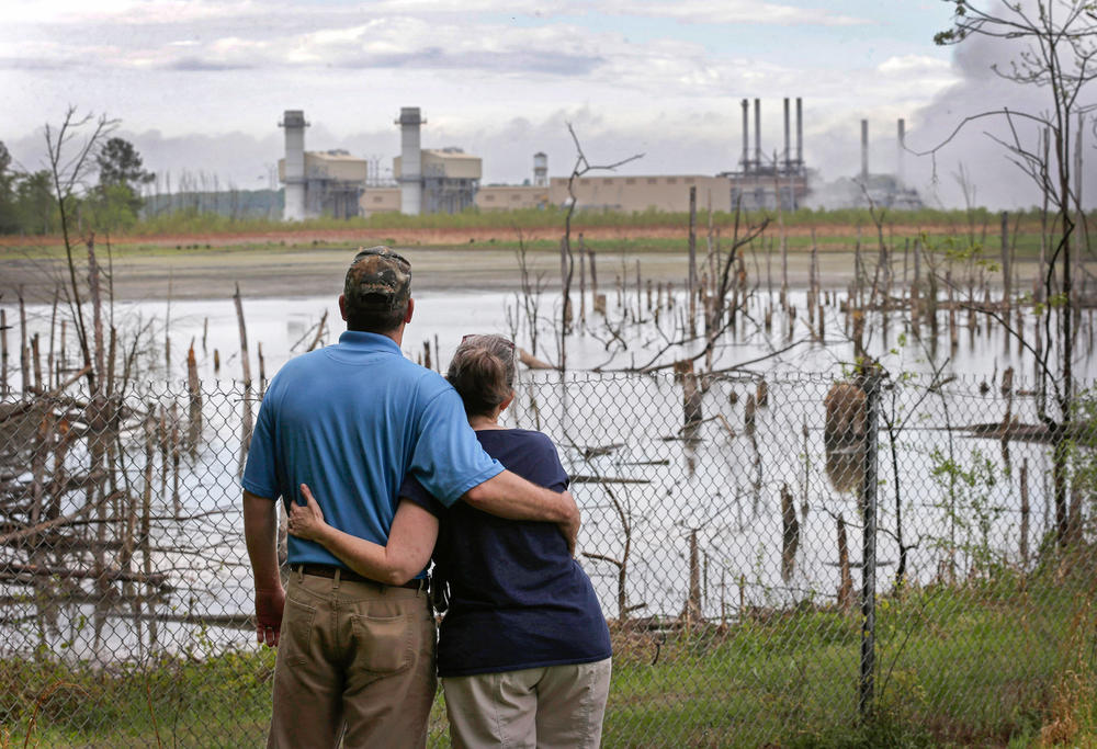 Bryant and Sherry Gobble embrace as they look from their yard across an ash pond full of dead trees toward Duke Energy's Buck Steam Station in Dukeville, on April 25, 2014. Government lawyers sought to have Duke Energy held liable for environmental damage from the leak that left the Dan River coated in hazardous coal ash, harming fish, birds and amphibians.