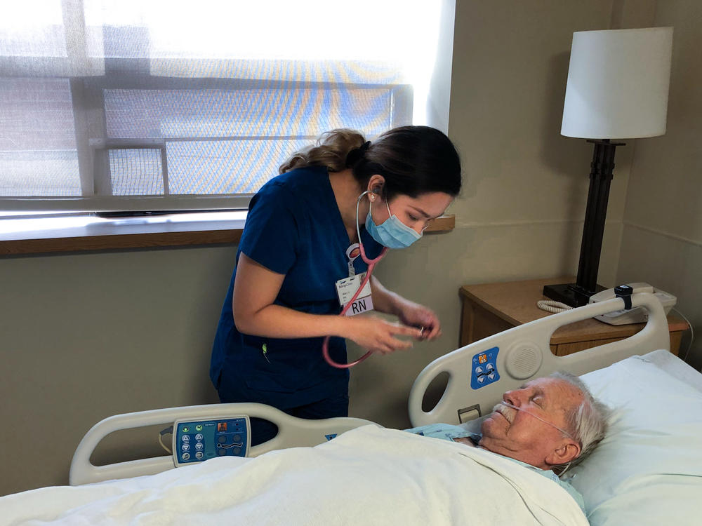 Mary Venus, a nurse from the Philippines, checks on a patient inside the in-patient surgical recovery unit at Billings Clinic in Billings, Mont.