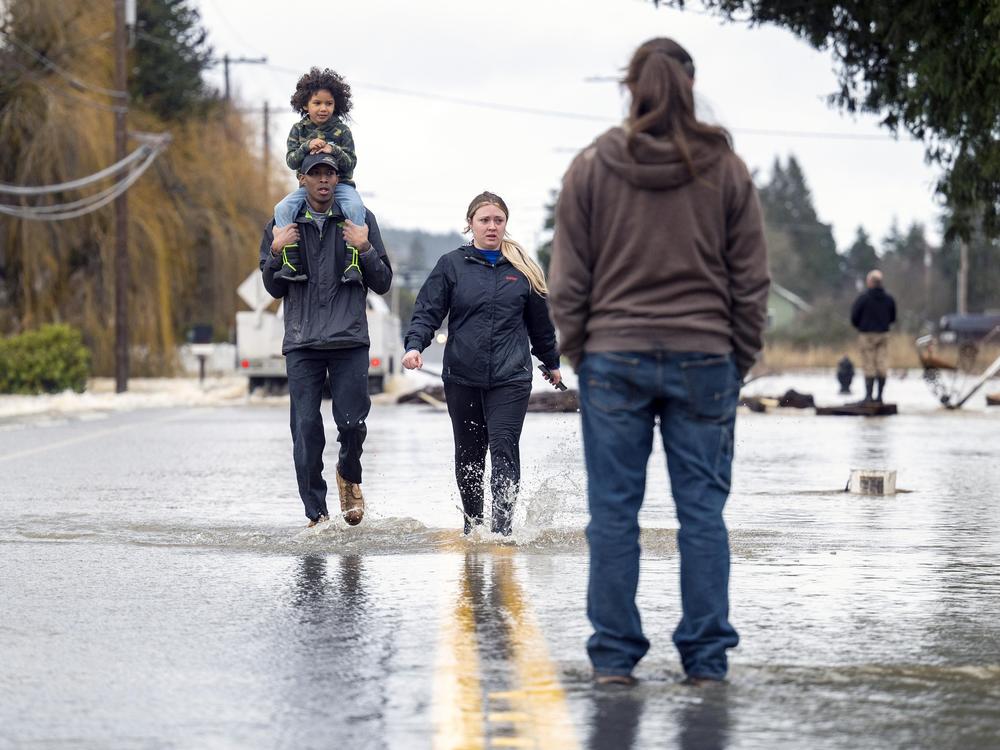 Reggie Brown, of Centralia, carries his daughter, Ocean, 4, on his shoulders as he walks through the floodwaters on Highway 507 with his wife, Jonell Brown, on Friday in Centralia, Wash. The highway had flooded after heavy rains caused the Skookumchuck River to rise about its northern banks.