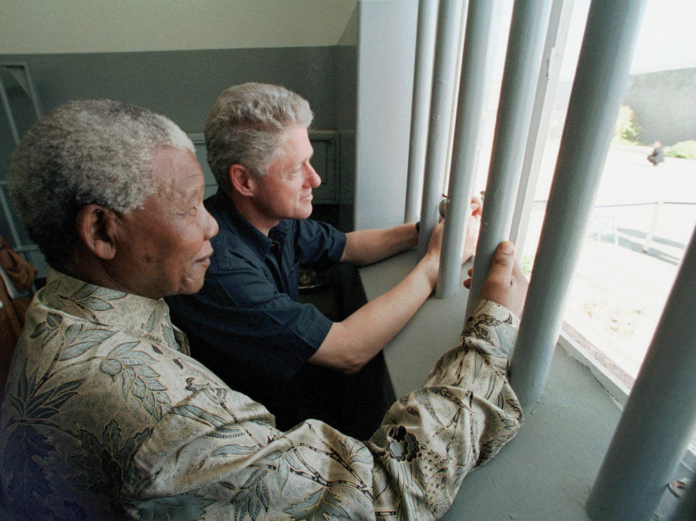Nelson Mandela and former U.S. President Bill Clinton look to the outside from Mandela's Robben Island prison cell in Cape Town, South Africa, in this photo from March 27, 1998.