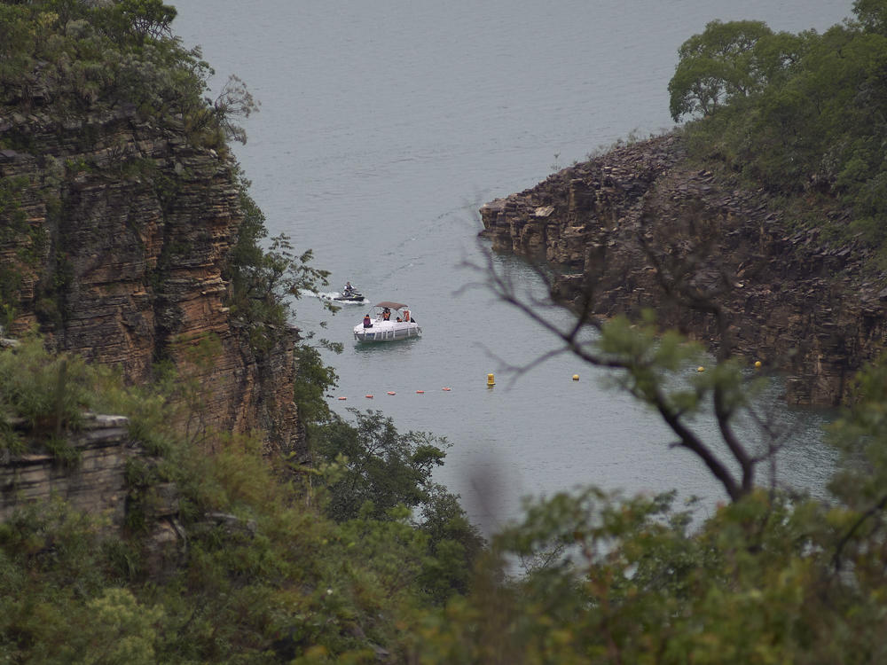 A boat navigates on the Furnas reservoir on Sunday after a massive slab of rock broke away from a cliff and toppled onto pleasure boaters on Saturday, killing at least 10 people near Capitolio city, Brazil.