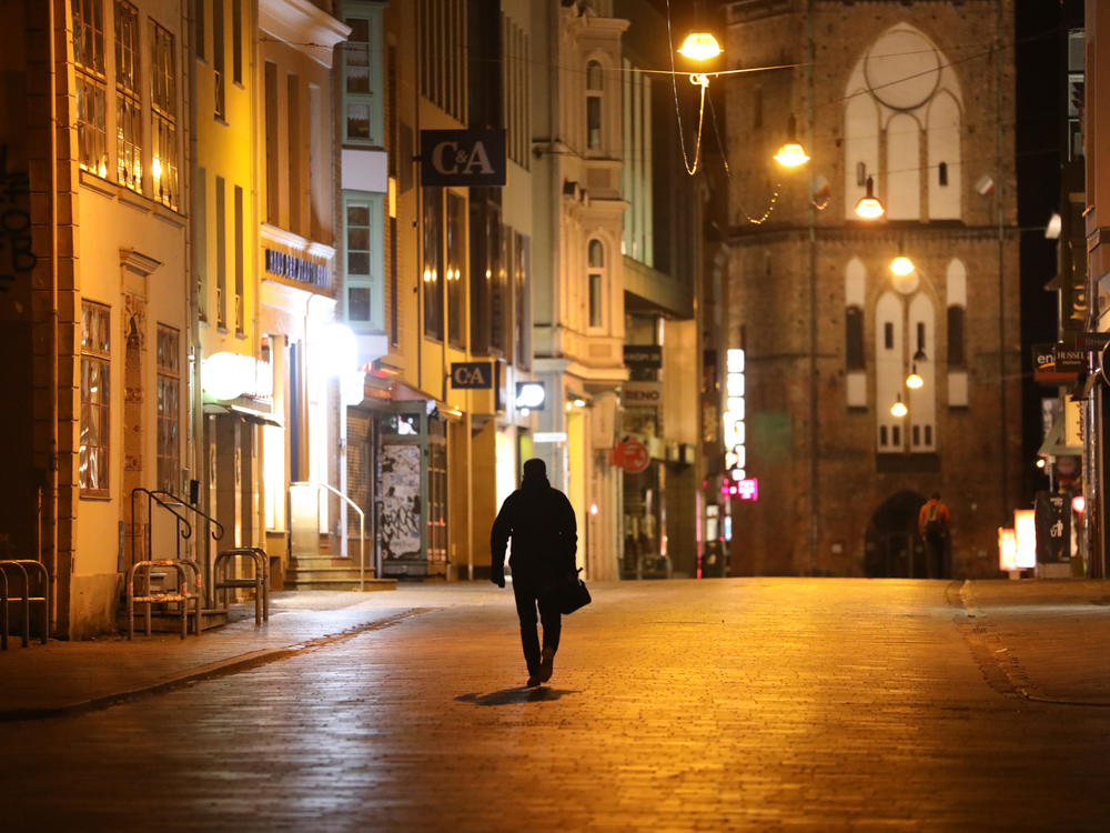 A man walks along an empty street in Rostock, Germany, on Jan. 6. The country has enforced a new set of measures to control the spread of omicron.