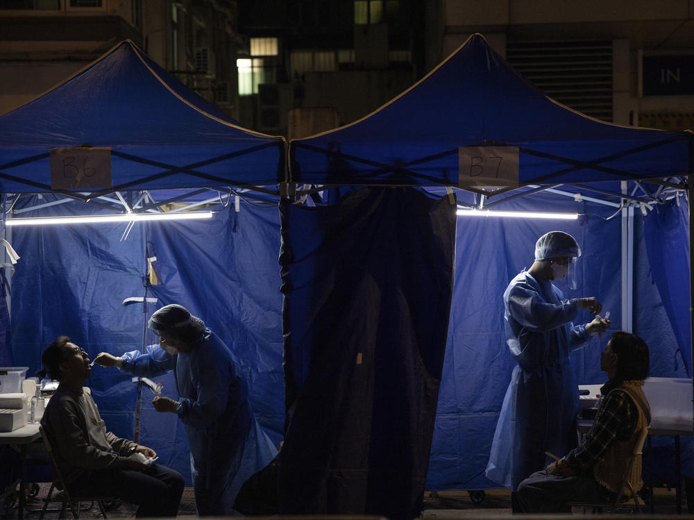 Health workers administer COVID tests outside a building placed under lockdown in Hong Kong on Jan. 6. Hong Kong is imposing strict new COVID measures for the first time in almost a year as the omicron variant seeps into the community.