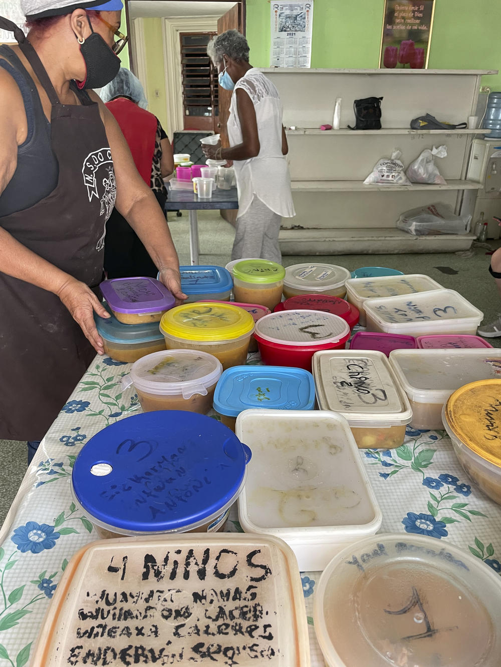 A volunteer fills up tupperware containers with beef stew.