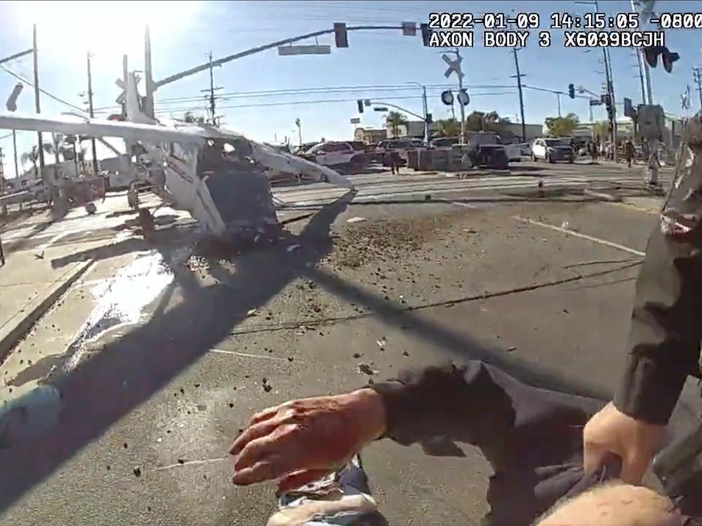 An image from a Los Angeles police officer's body-worn camera shows the pilot of a small plane being dragged to safety after his aircraft crash-landed in the path of an oncoming commuter train.