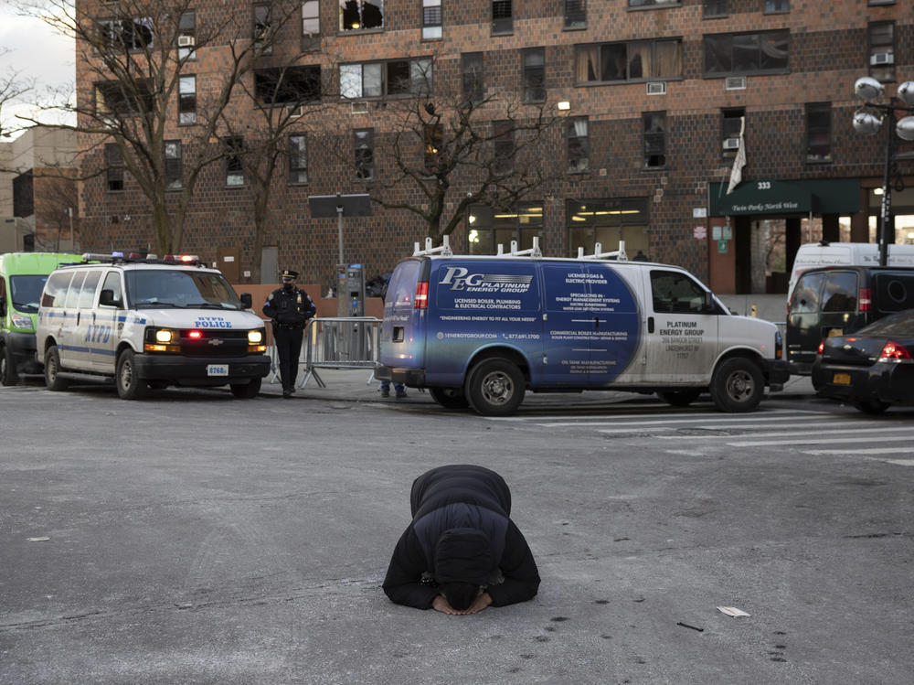 A person prays Monday outside the Bronx apartment building where the fire occurred a day earlier.