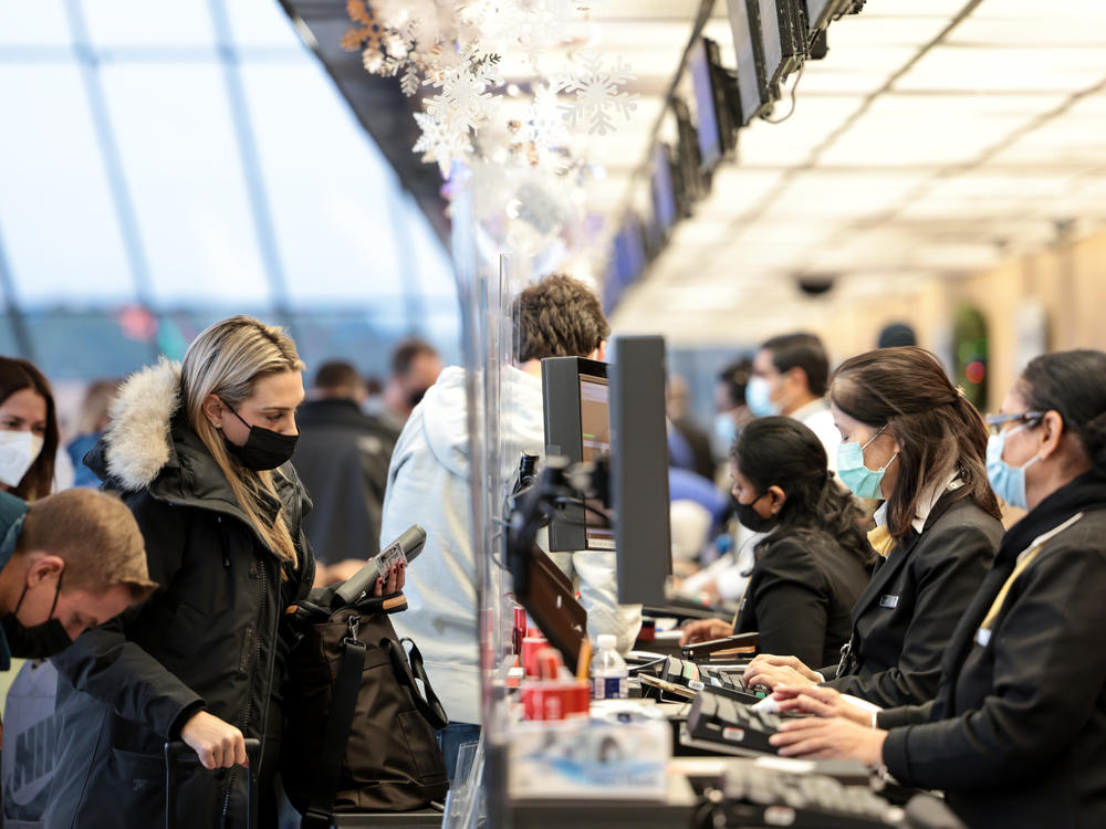 A woman checks in for her flight at a United Airlines counter at Dulles International Airport on December 27, 2021.