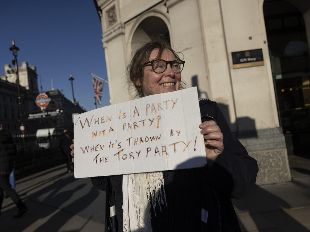 A protester holds a sign outside of Parliament in London after the weekly Prime Minister's Questions session, in which Boris Johnson said he joined staff for an outdoor party at 10 Downing Street in May 2020.