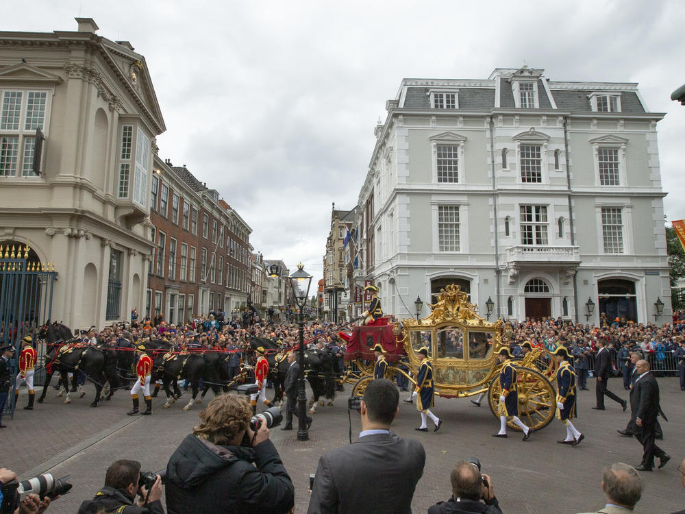 Footmen walk alongside the Golden Carriage as Netherlands' King Willem-Alexander and Queen Maxima arrive at Noordeinde Palacey on Sept. 17, 2013.
