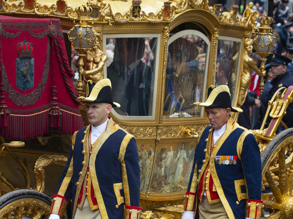 Footmen walk alongside the Golden Carriage as Netherlands' King Willem-Alexander and Queen Maxima arrive at Noordeinde Palace on Sept. 17, 2013.