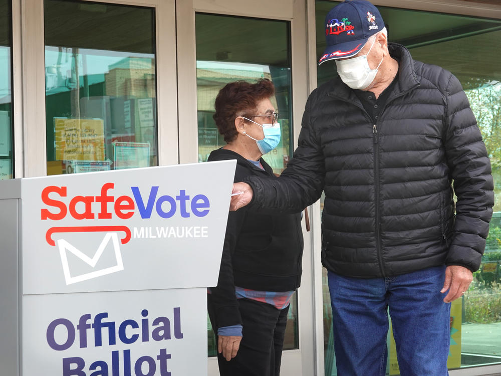 Residents drop mail-in ballots in an official ballot box outside of a Milwaukee library on Oct. 20, 2020.