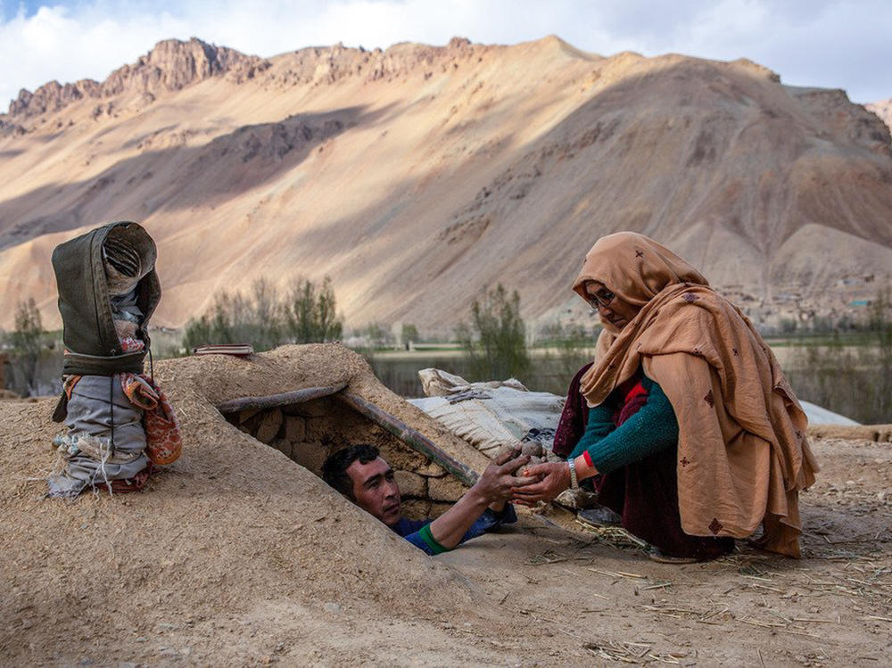 Roqia Qasqari, right, who lives in Gero village in Afghanistan's Bamyan Province, inspects potatoes stored from a previous harvest. Snow was scarce over the winter, raising fears of a severe drought in 2021.