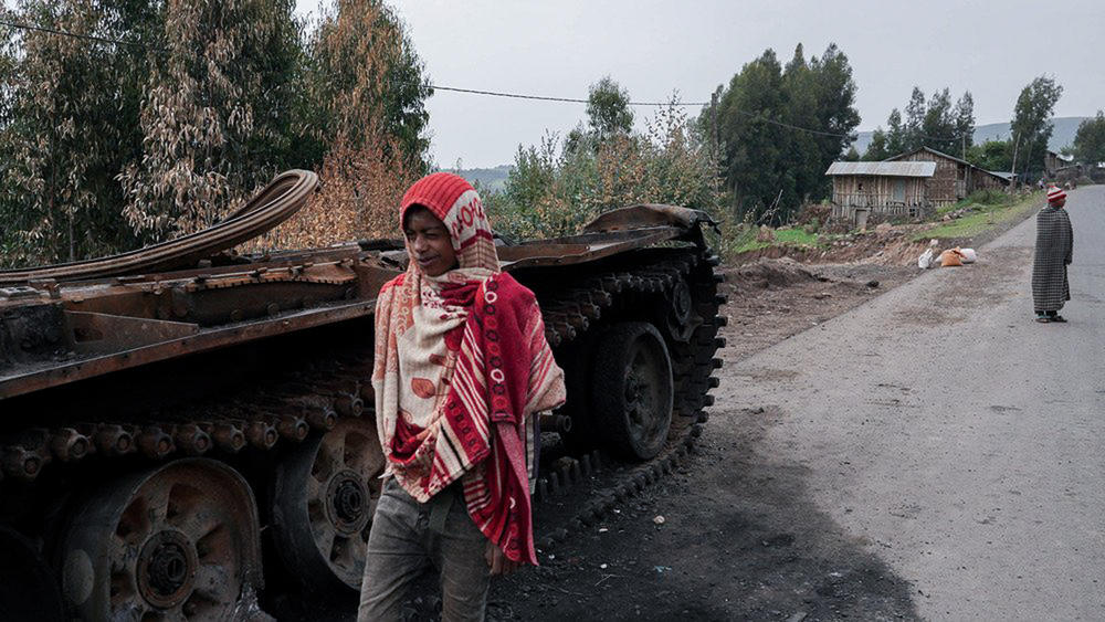 Residents walk past an abandoned tank on a main road in Amhara region, Ethiopia, in 2021, where hundreds of thousands of people have fled recent fighting — and in need of humanitarian assistance.