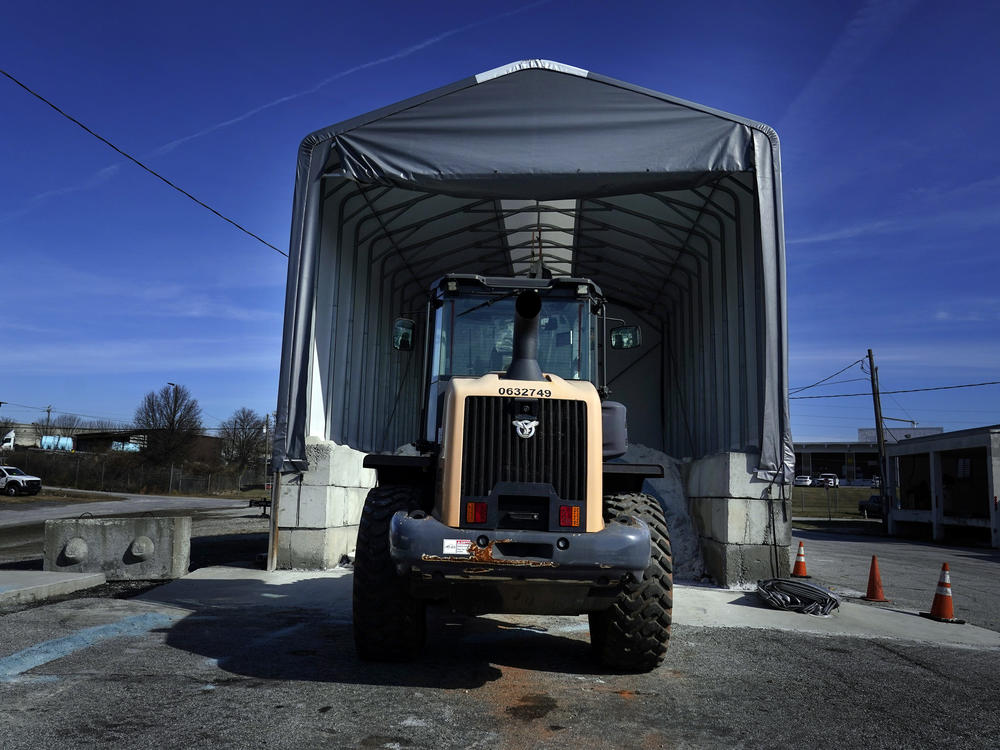 A tractor sits in front of a pile of salt used to create a brine that will help clear road of ice and snow ahead of a winter storm at the GDOT's Maintenance Activities Unit location on Friday, Jan. 14, 2022, in Forest Park, Ga.