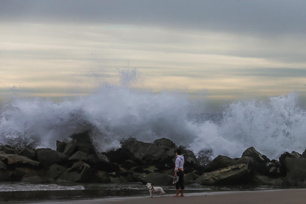 A man takes a picture of the big waves in the breakwater in Venice beach while a tsunami advisory was in effect on Saturday in Los Angeles.