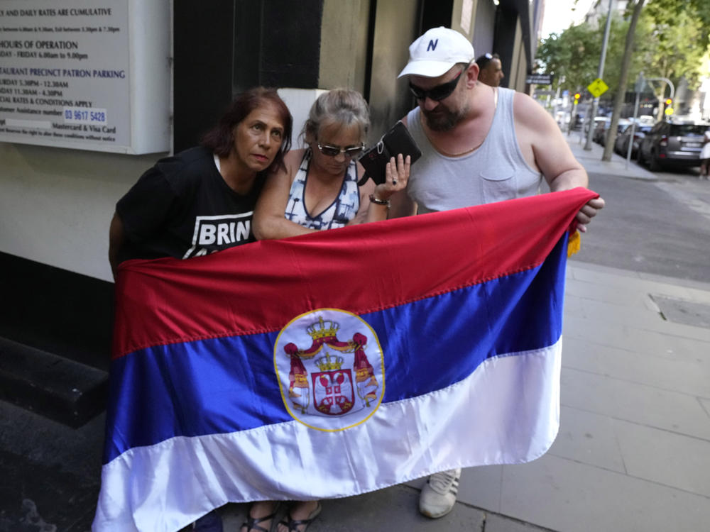Supporters of Serbia's Novak Djokovic listen to his ruling outside the lawyer's office of Djokovic in Melbourne, Australia, Sunday, Jan. 16, 2022.