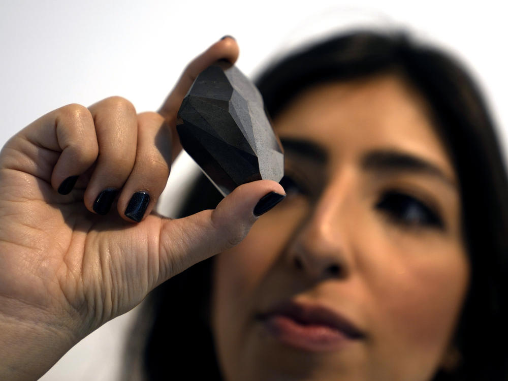 An employee of Sotheby's Dubai presents a 555.55 Carat Black Diamond called 