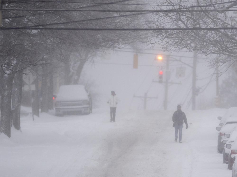 Pedestrians make their way down a partially plowed Murray Avenue Monday, Jan. 17, 2022, in Squirrel Hill neighborhood of Pittsburgh.