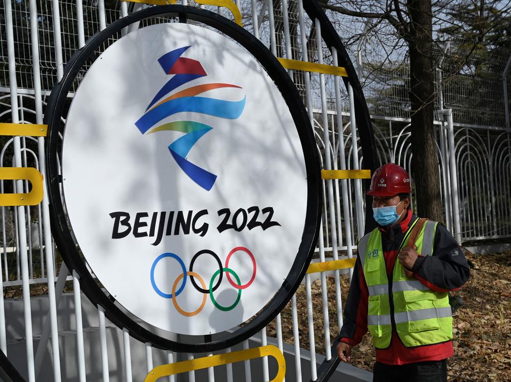 A construction worker walks past the Beijing 2022 Winter Olympic Games logo on a street in Beijing on December 11, 2021.