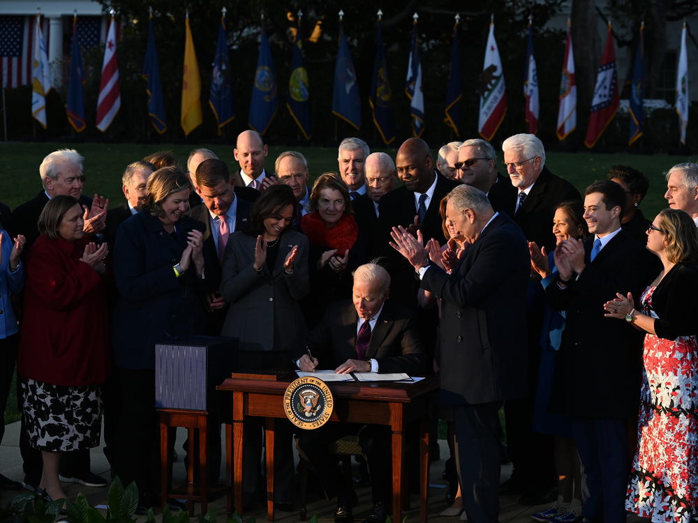 President Biden signs the infrastructure bill into law on Nov. 15, surrounded by lawmakers and members of his Cabinet.