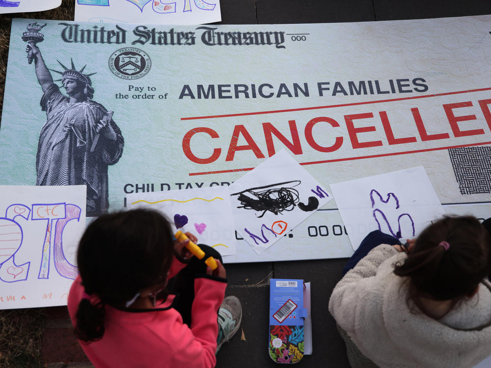 Children draw on top of a canceled check prop during a rally in favor of the child tax credit in front of the U.S. Capitol on Dec. 13, 2021, in Washington, D.C.