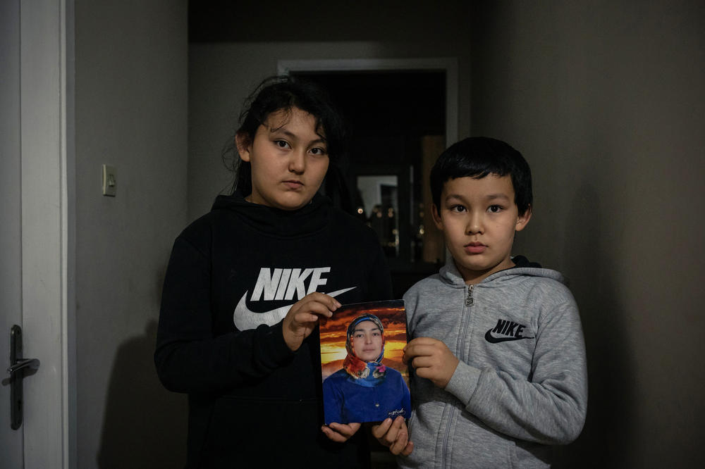 Aysu and Lütfullah hold a picture of their mother, Meryem Aimati, at their home in Istanbul. The children have not seen their mother for over two years, since they were released from state boarding schools and brought back to Turkey with their father.