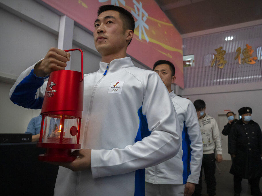 An official holds a lantern with the Olympic flame during an event to display the Olympic torch and flame at the Beijing University of Posts and Communications in Beijing, Thursday, Dec. 9, 2021.