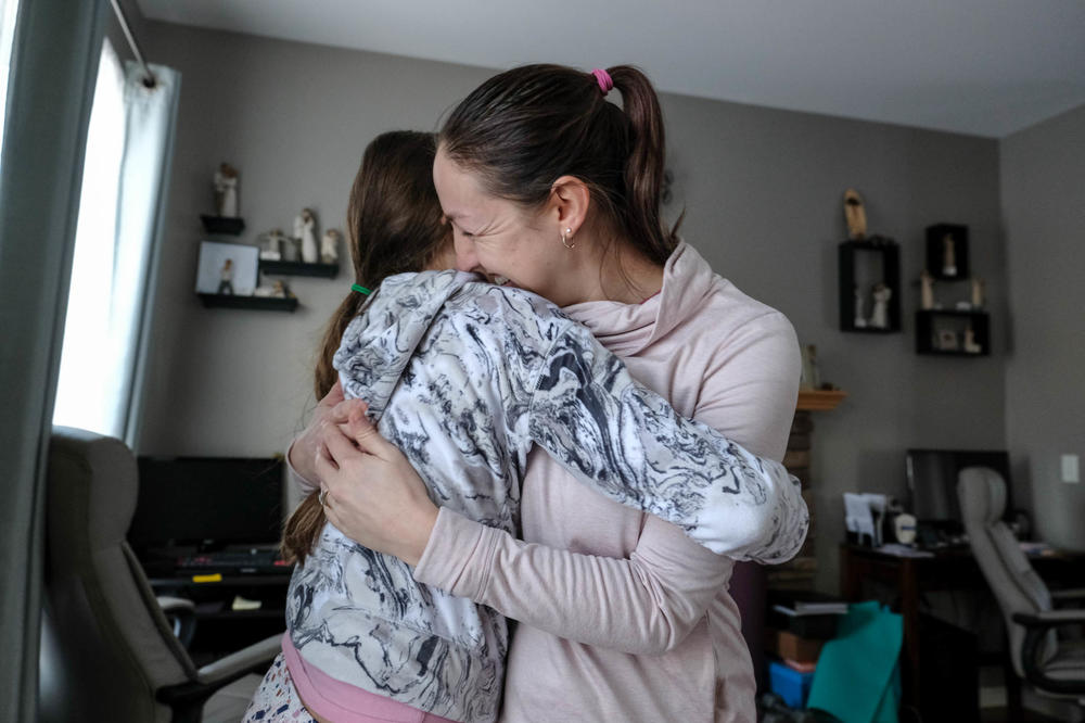 Avah and her mom, Sara Lamie, embrace at their home.
