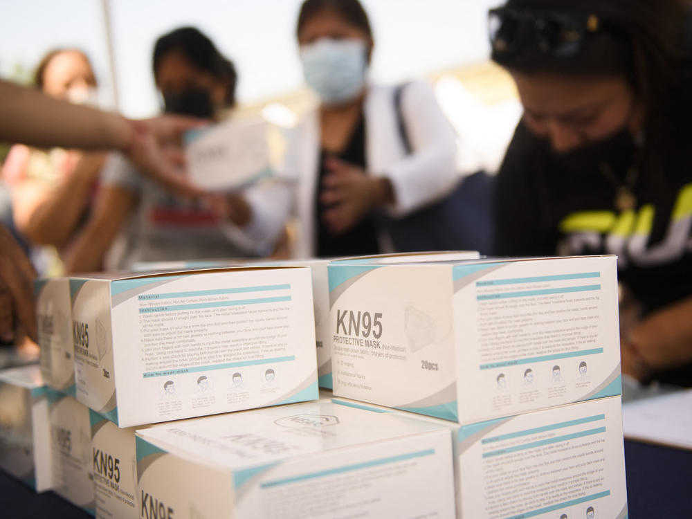 People receive boxes of KN95 face masks during a back to school event offering school supplies, COVID-19 vaccinations, face masks, and other resources for children and their families at the Weingart East Los Angeles YMCA in August.