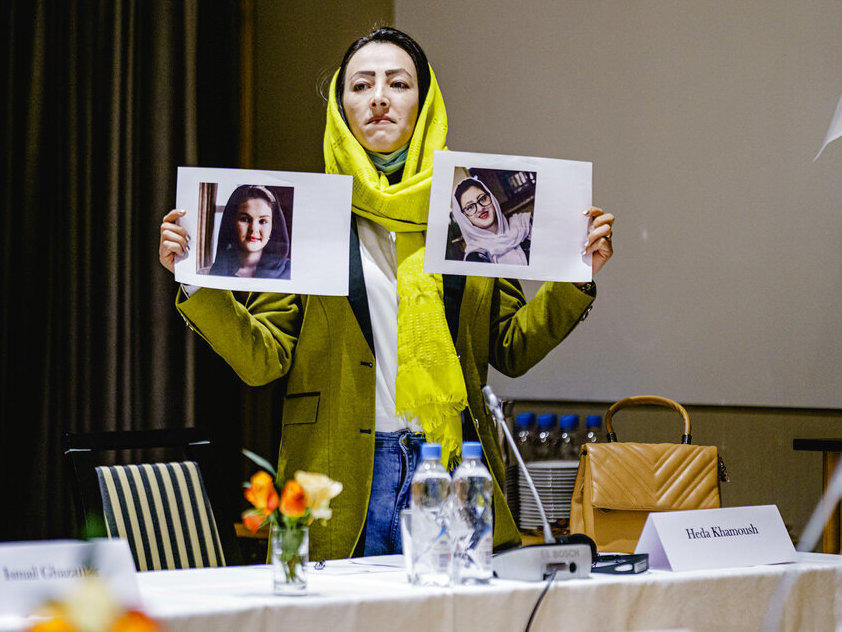 Delegate from the Afghan civil society Heda Khamoush holds up photos of two women who have vanished, ahead of a meeting in Oslo, Norway, Monday.