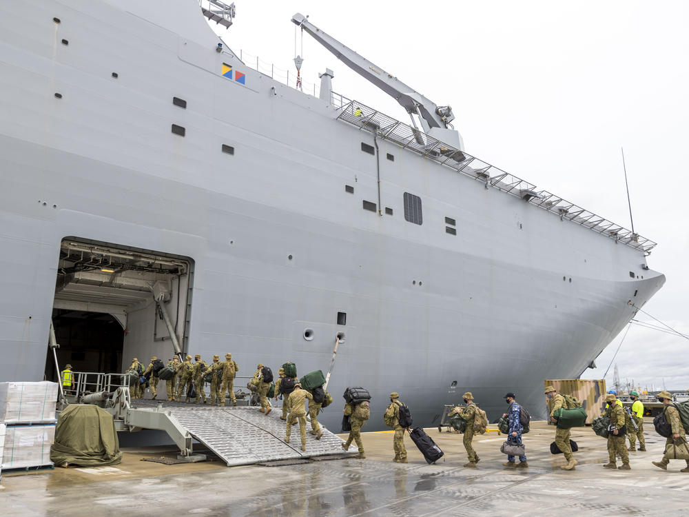 Soldiers load onto HMAS Adelaide at the Port of Brisbane before departing for Tonga on Thursday. Nearly two dozen sailors aboard the Adelaide have tested positive for the coronavirus, officials said Tuesday, raising fears they could bring the disease to Tonga, which has so far managed to avoid any outbreaks.