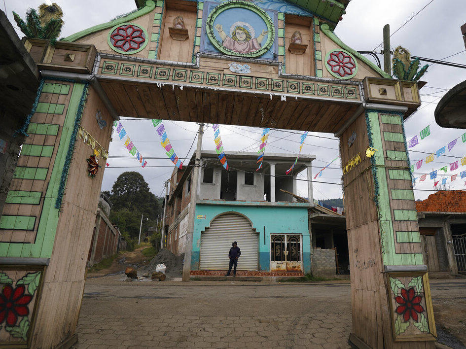 A community police officer stands guard at the main gate to the Purepecha Indigenous community of Comachuen, Michoacan state, Mexico, Wednesday, Jan. 19, 2022.