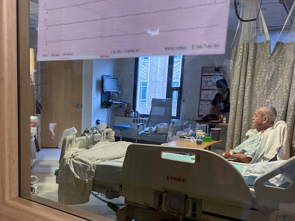 A patient sits in bed on the COVID-19 ward at Harborview Medical Center in Seattle earlier this month. COVID patients are filling up acute care units here and at hospitals across the country, even though omicron tends to cause milder cases.