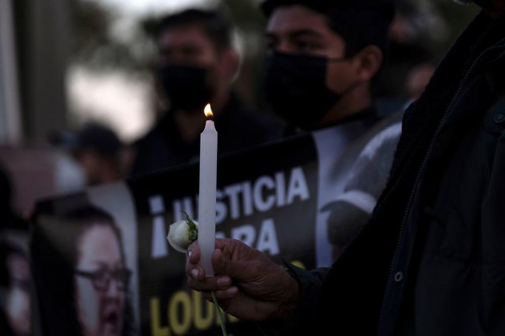 A person holds a rose and a candle as journalists and supporters protest the murders of their colleagues Lourdes Maldonado and Margarito Martinez, in front of the federal prosecutors building in Tijuana.