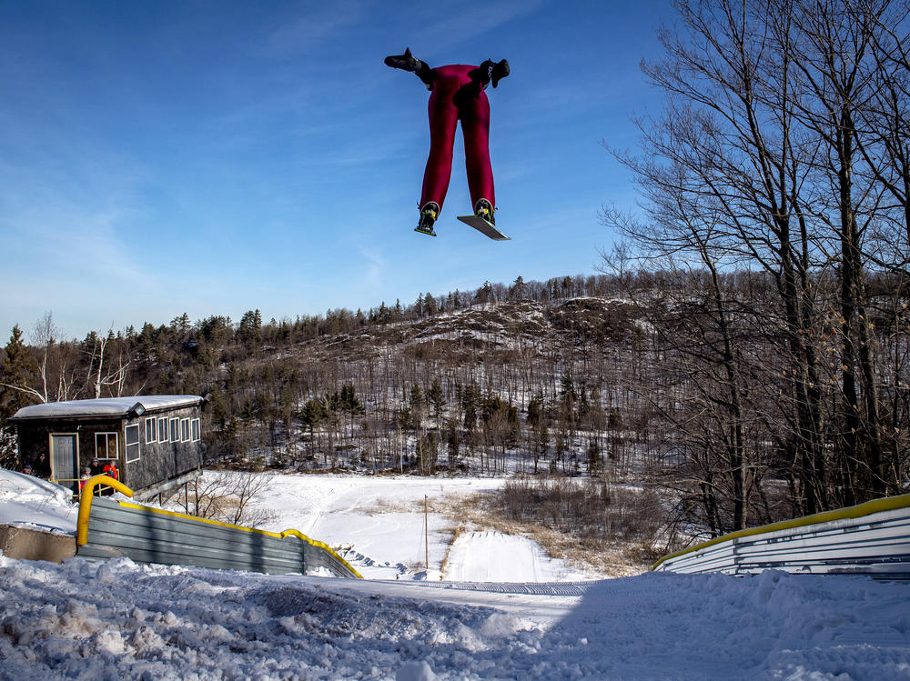 A ski jumper flies overhead on the 60-meter ski jump at the Suicide Hill Ski Bowl in Ishpeming, Mich. on March 7, 2021. The Suicide Hill Ski Bowl is home to 5 ski jumps - one being the infamous 90-meter Suicide Hill Ski Jump.