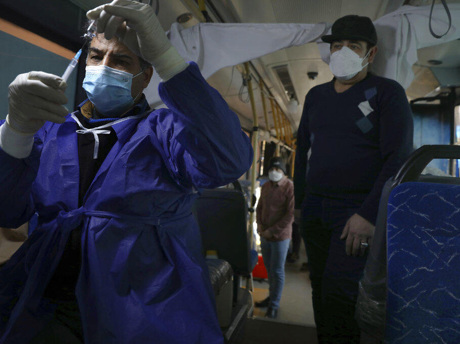 A health worker prepares a COVID-19 vaccine at a mobile vaccine clinic bus at the Grand Bazaar of Tehran, Iran, Saturday, Jan. 22, 2022.