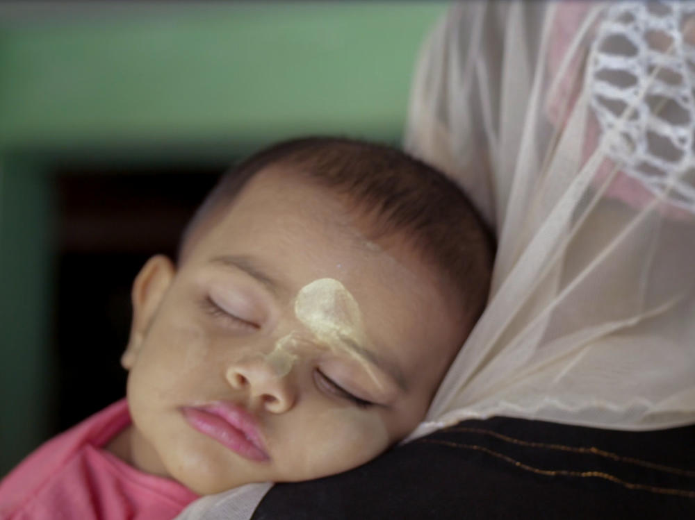 A scene from <em>Midwives</em>: A baby whose face is adorned with thanaka — a kind of sunscreen made from wood bark.