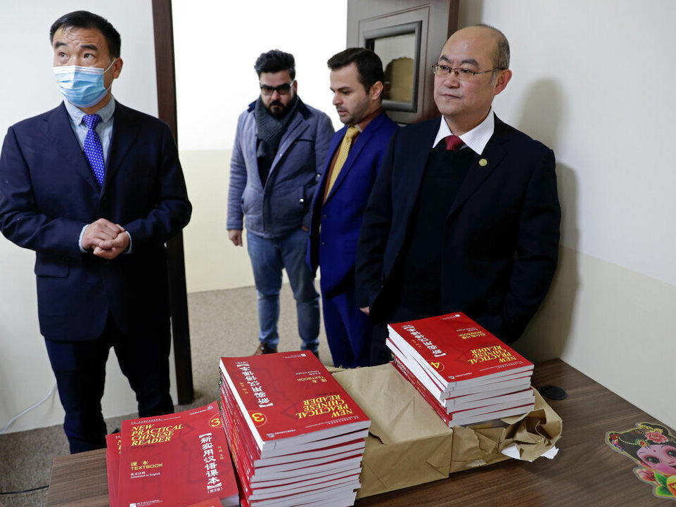 Chinese lecturer, Zhiwei Hu, left, teachers and officials of the Chinese Language Department stand in front of Chinese language books intended for students in Salahaddin University in Irbil, Iraq, Wednesday, Jan. 19, 2021.