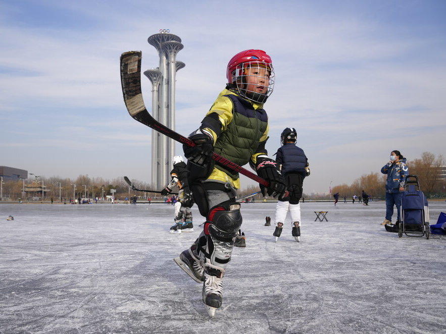 A child practices ice hockey near the Beijing Olympics Tower in Beijing, China, Tuesday, Jan. 18, 2022.