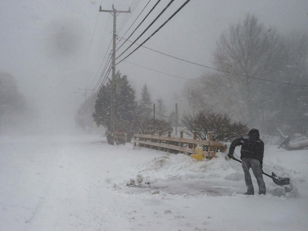 A man shovels snow in near whiteout conditions during a nor'easter in Marshfield, Mass., on Saturday.