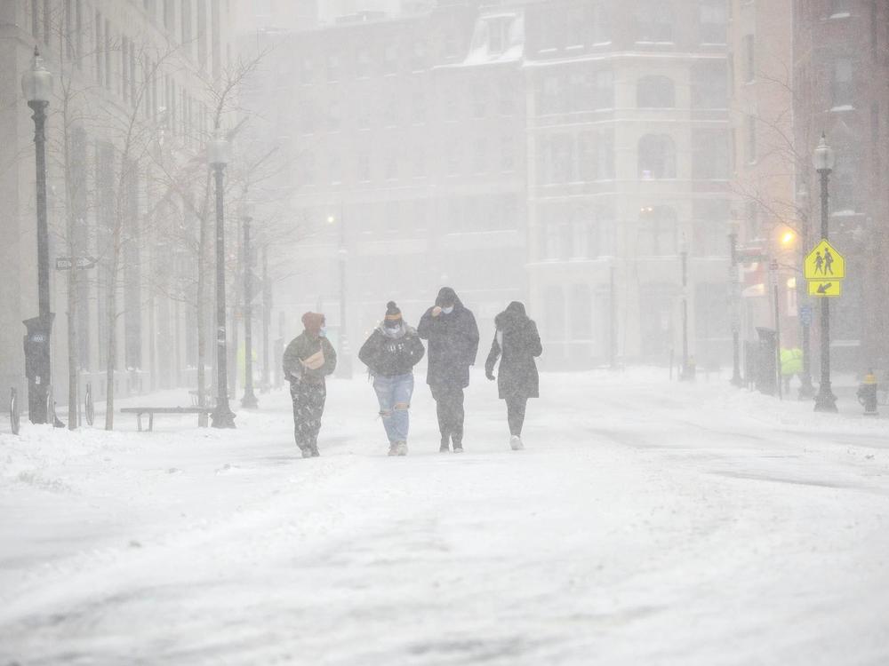 A group of people battle with wind and snow as they make their way along Broad Street in Boston.