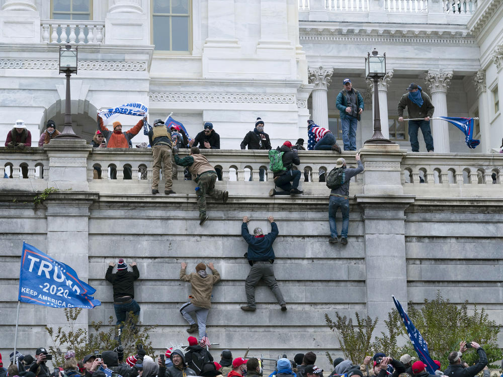 Trump supporters climb the west wall of the U.S. Capitol on Jan. 6, 2021. A new survey finds 1 in 10 Americans say violent protests are justified.