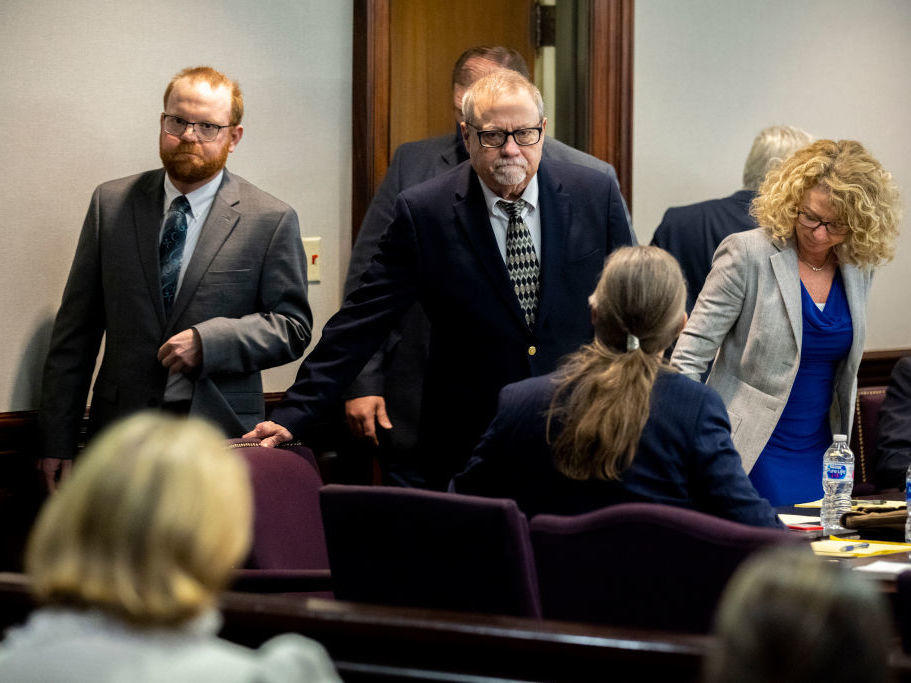 Greg McMichael (center) and his son Travis McMichael (left) look at family members seated in the gallery when they walk into the courtroom for the reading of the jury's verdict for themselves and a neighbor, William 