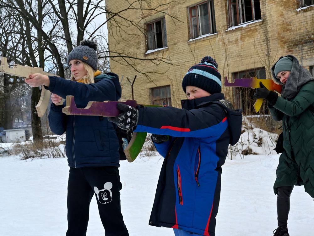 Civilians hold wooden replicas of Kalashnikov rifles, as they take part in a training session at an abandoned factory in the Ukrainian capital of Kyiv on January 30, 2022.